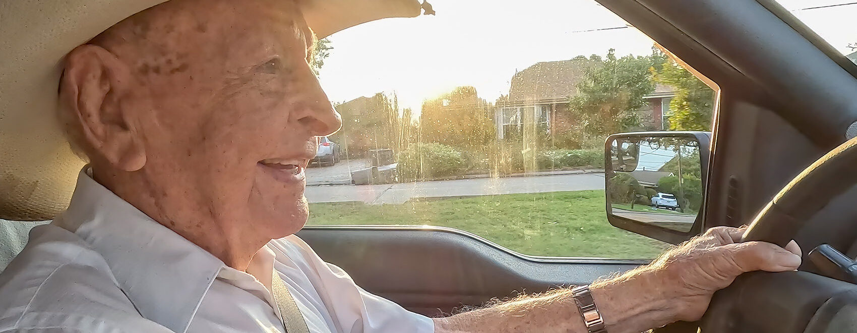elderly man wearing straw hat driving vehicle