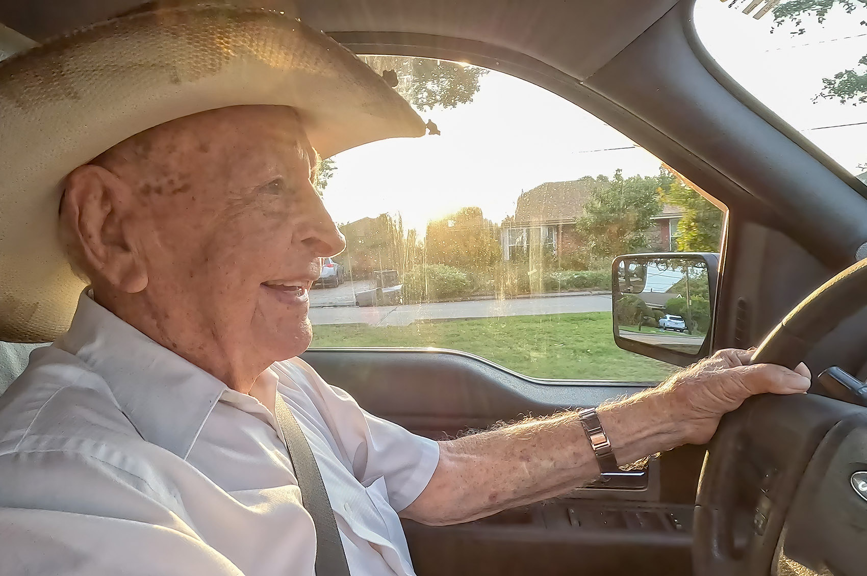 elderly man wearing straw hat driving vehicle
