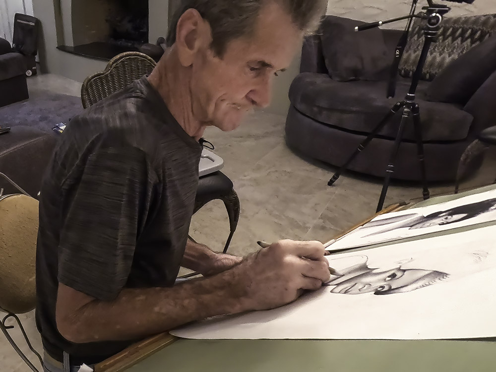 man with moustache in t-shirt using pencil to draw woman's portrait
