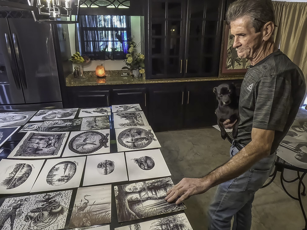 Lafitte artist looks over drawing laid out on table.