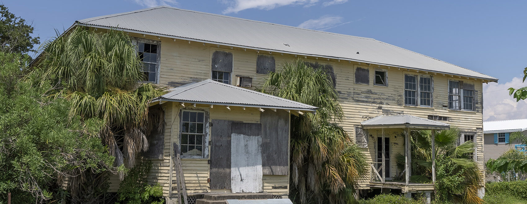 dilapidated two story yellow wood building on Grand Isle