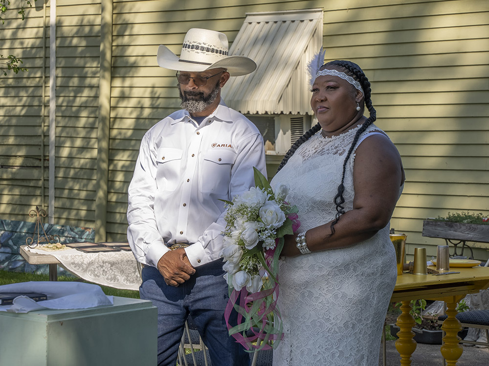 man in white shirt and white cowboy hat with woman in white dress with white flower boquet at Creole wedding