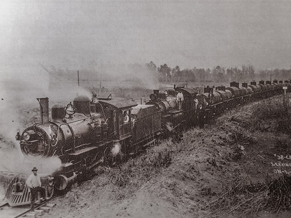 black and white photographof steam engine pulling tank cars