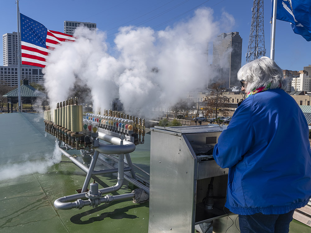 woman with gray hear and blue coat plays a calliope atop the steamboat Natchez on the New Orleans riverfront