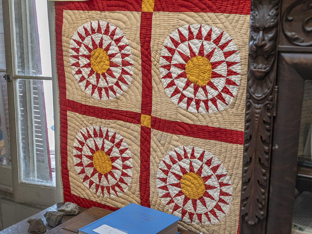 old quilt pattern  in red, yellow, white and tan, hanging on display
