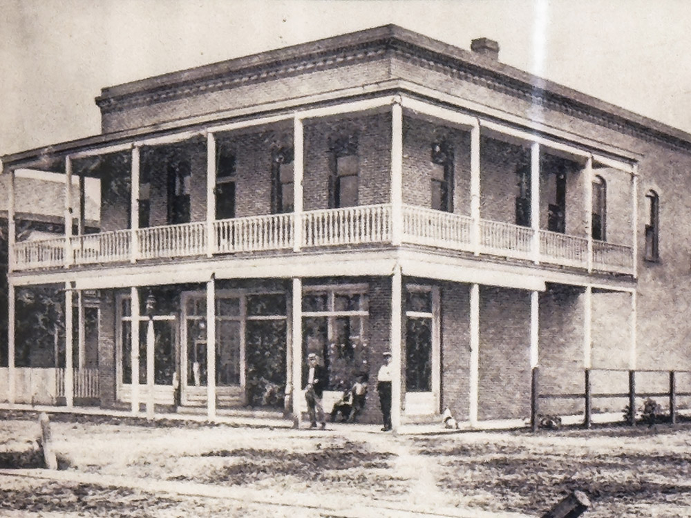 old photograph of street corner general store in 2 story brick building.