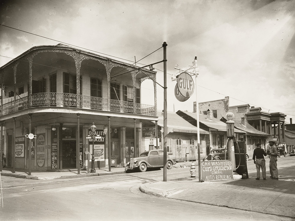 black and white photograph of new orleans street corner with two men grocery and gas station