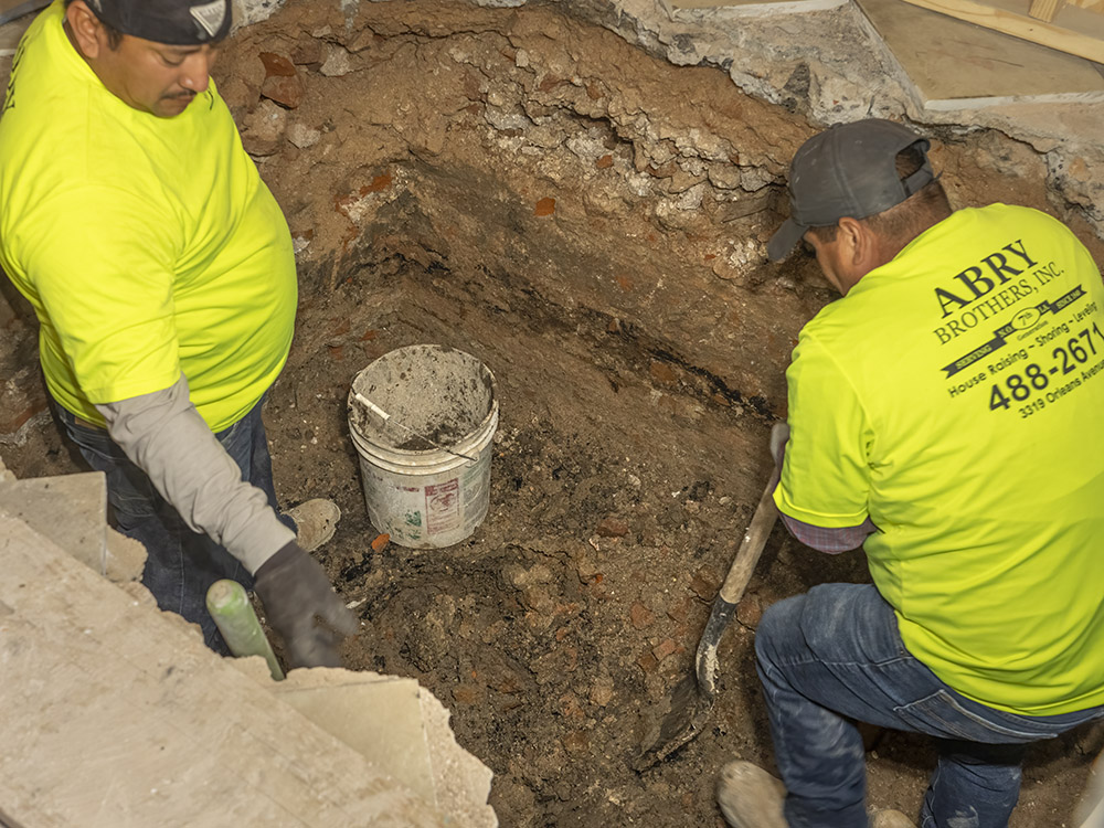 two men in jeans and yellow shirts dig hole