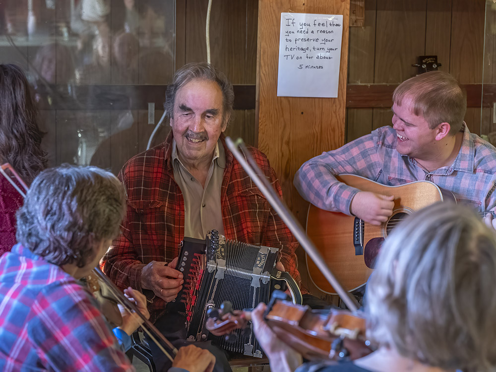 man with moustache and red plaid shirt plays accordion next to man playing guitar at Savoy Music Center