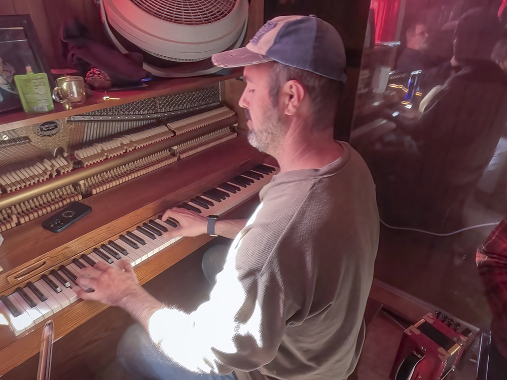man with cap and gray shirt plays piano