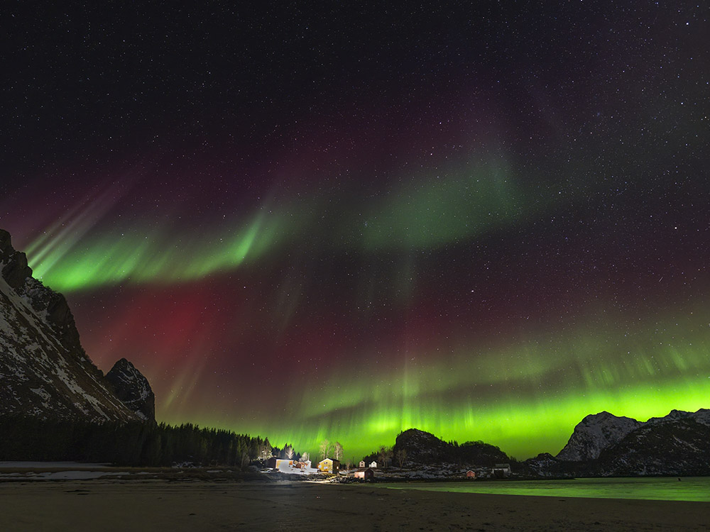 green, red, purple white northern light display above home in Norway
