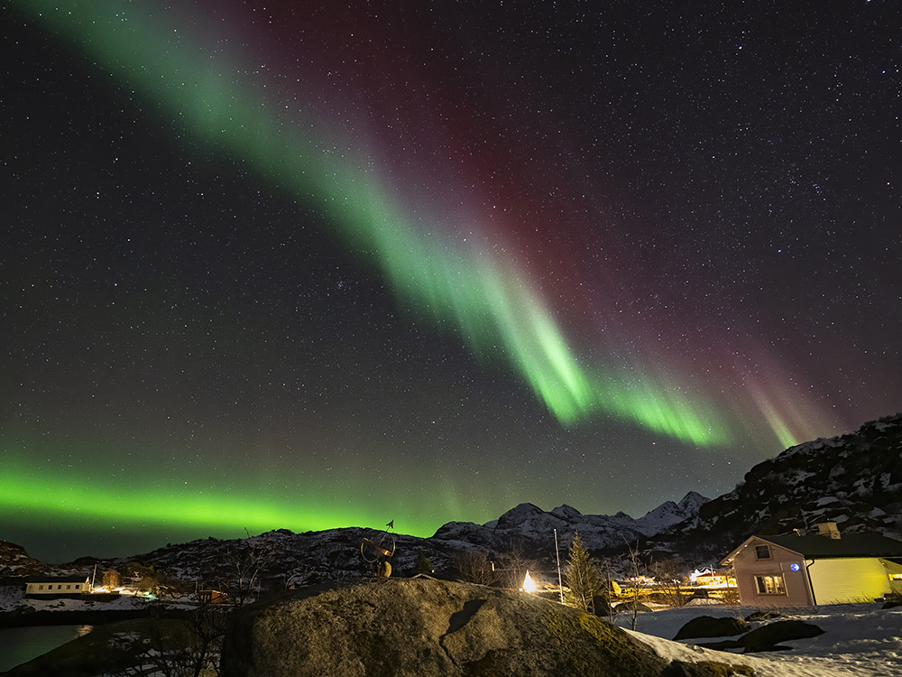 green, blue and red aurora above buildings in arctic
