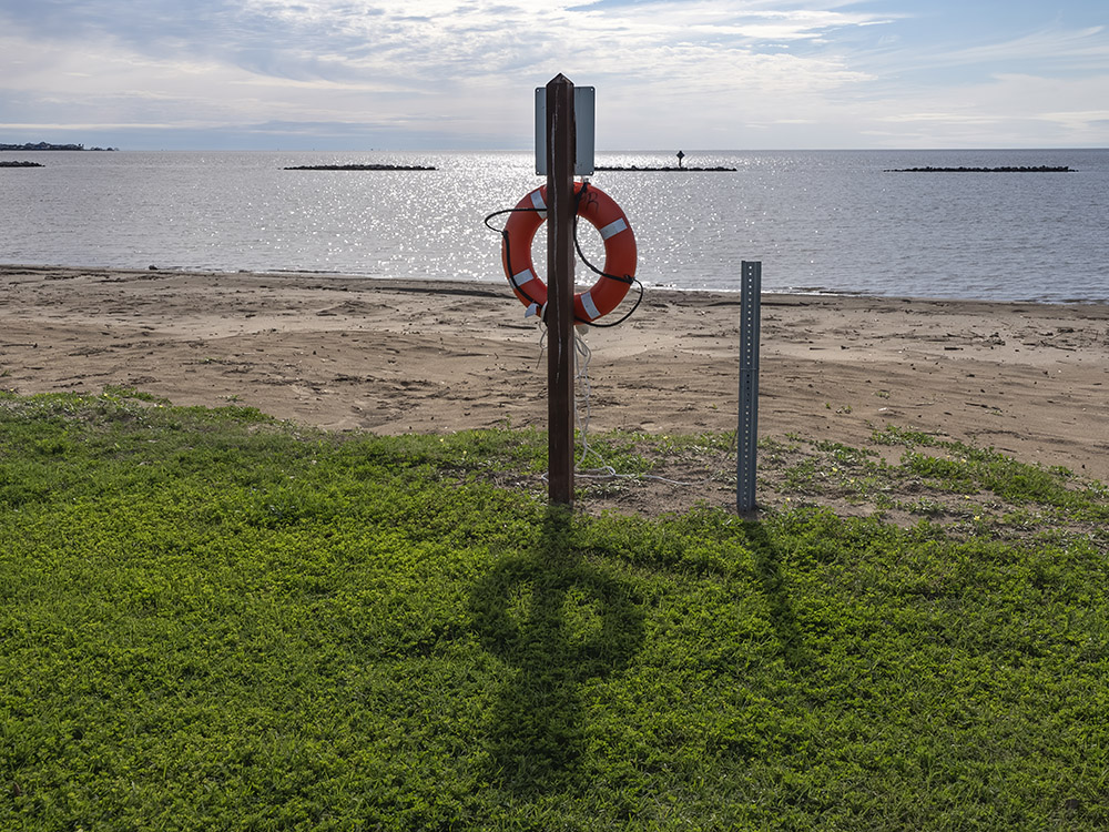 sandy beach and water with rescue ring on post