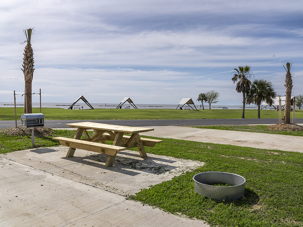 picnic table fire pit and parking for rv with pavilions and beach in distance