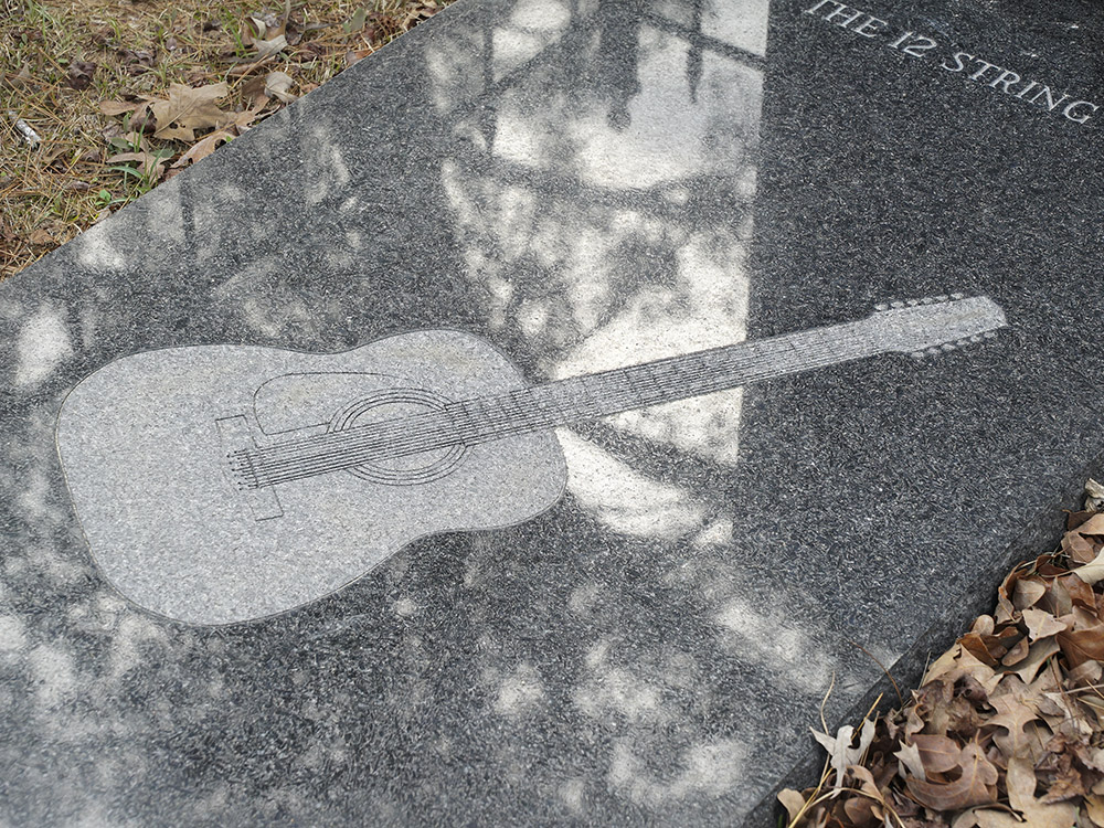 12 string guitar etched into granite burial