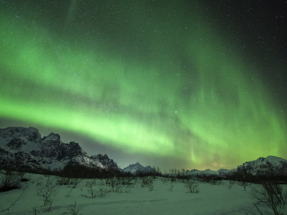 northern lights above snow and mountains in Norway