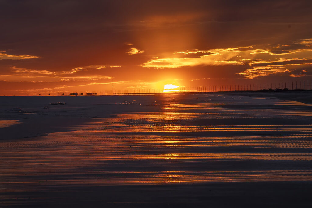 brilliant orange sunset over beach and waterfront