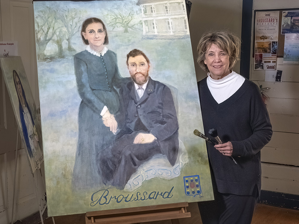 woman artist stands next to large portrait of man and woman