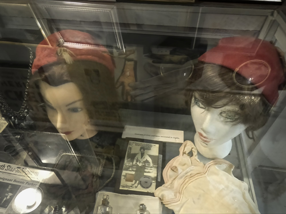 red women hats on mannequin heads and other artifacts in display case