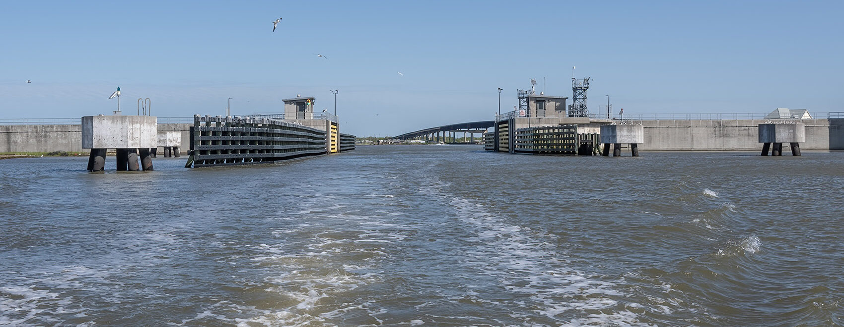 flood gate and boat wake under clear blue skies