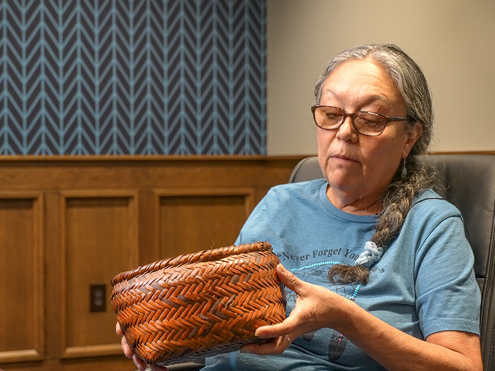 woman with braided hair and classes holds brown river cane basket