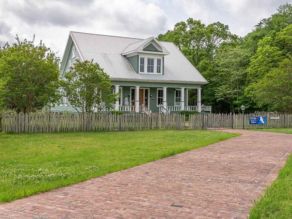 blue wooden house with white columns on front porch and dormer window