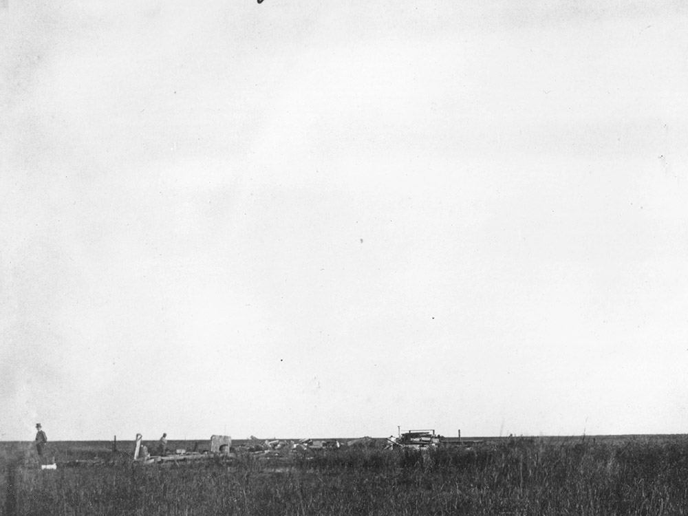 black and white image of hurricane damage and man standing nearby