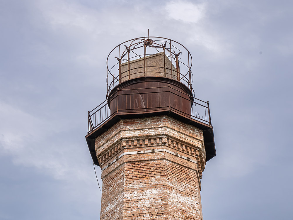 rusted metal top of a red brick lighthouse