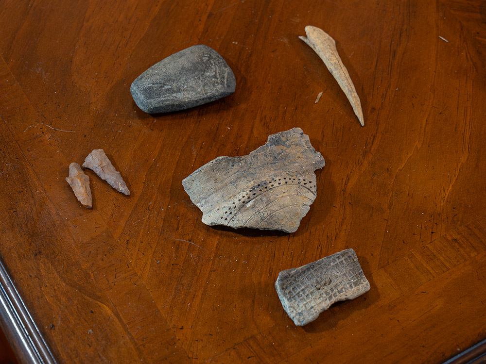 piece of native pottery, arrow points and stone tool