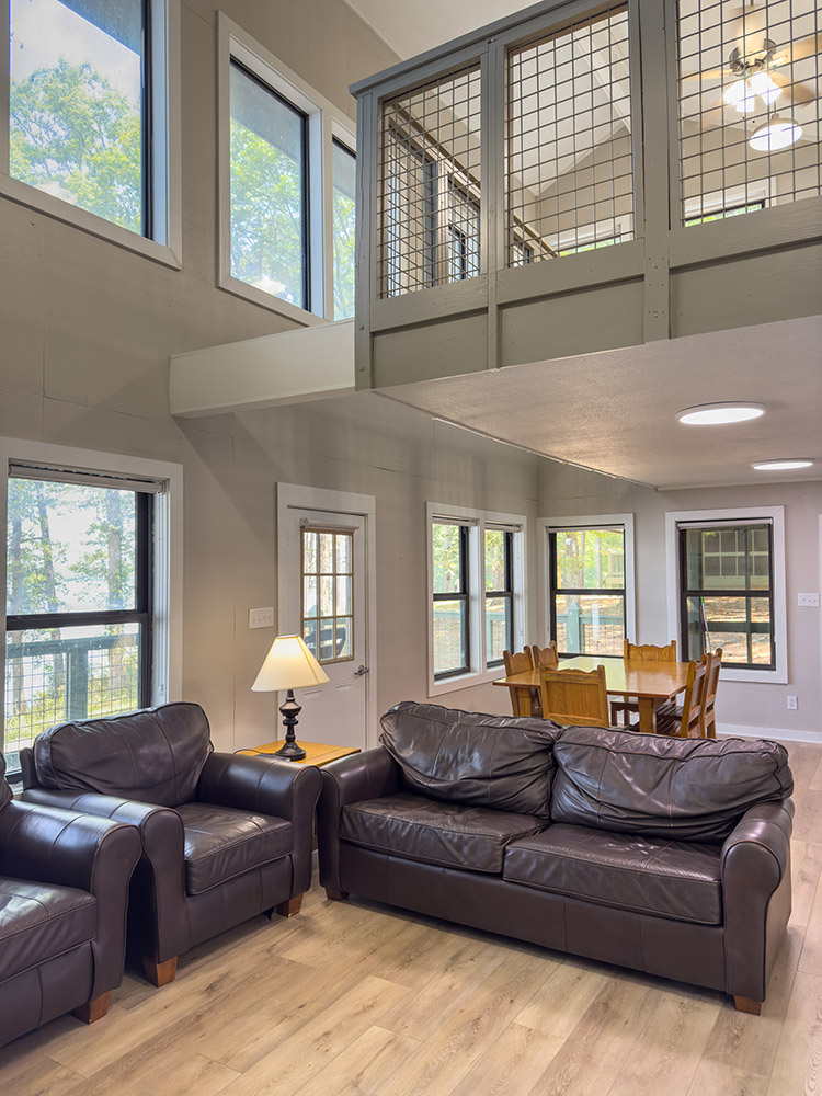 cabin living room with brown leather furniture, table and chairs and 2nd story loft