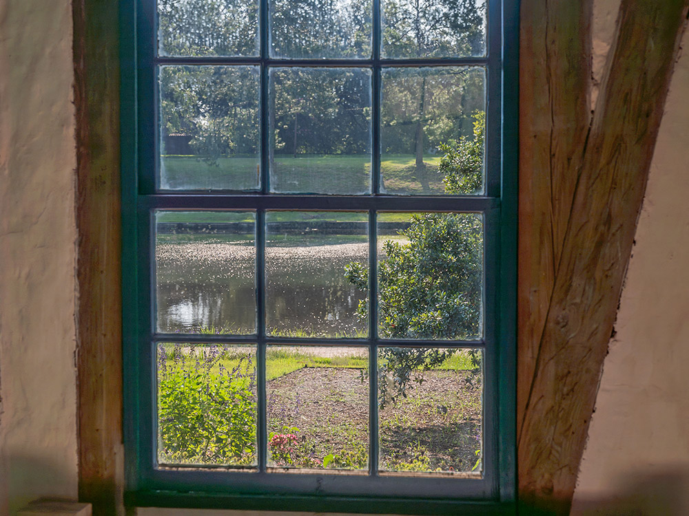 view of garden and lake through wood framed window