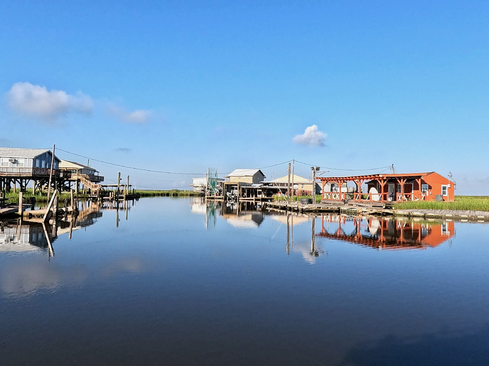 fishing camps along a bayou reflection in the still water under blue sky