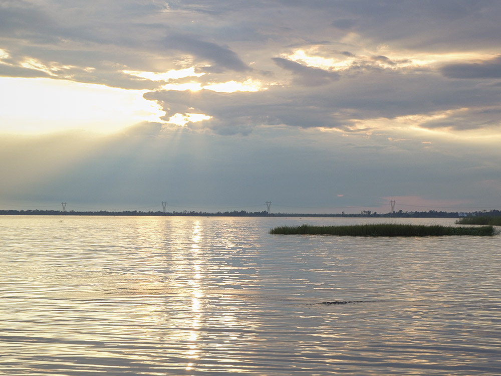 late afternoon sun behind clouds over lake