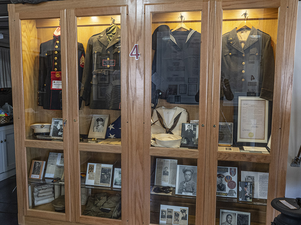 wood display case of military uniforms and photographs