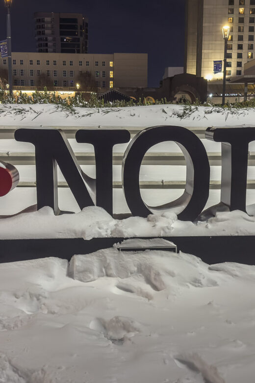 A black and read sign with letters I NOLA and red fleur de lis showing heaving snow in New Orleans