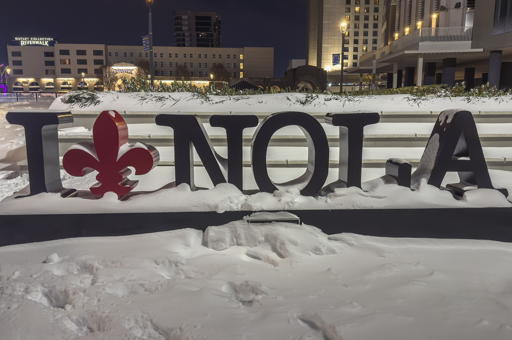 A black and read sign with letters I NOLA and red fleur de lis showing heaving snow in New Orleans