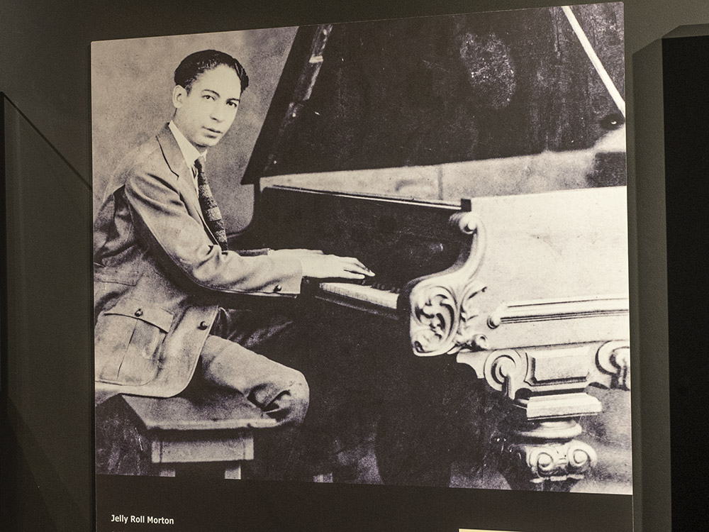 black and white photo of man playing grand piano, jelly roll morton