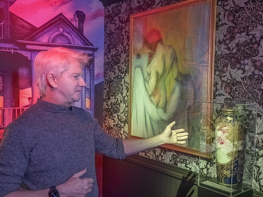 man pointing to Japanese ceramic vase near painting of woman