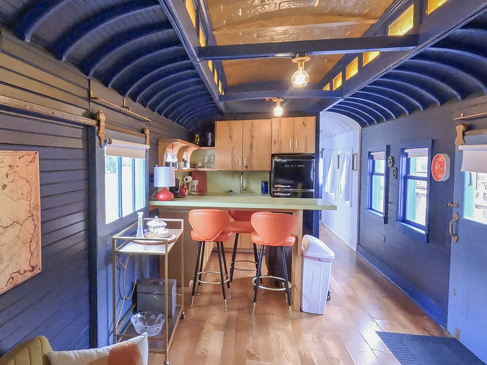 blue painted interior with kitchen and bar area with orange chairs