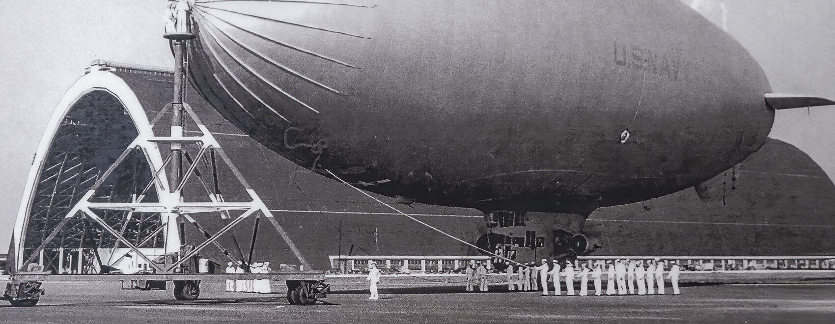 black and white photo of Navy blimp near large hangar