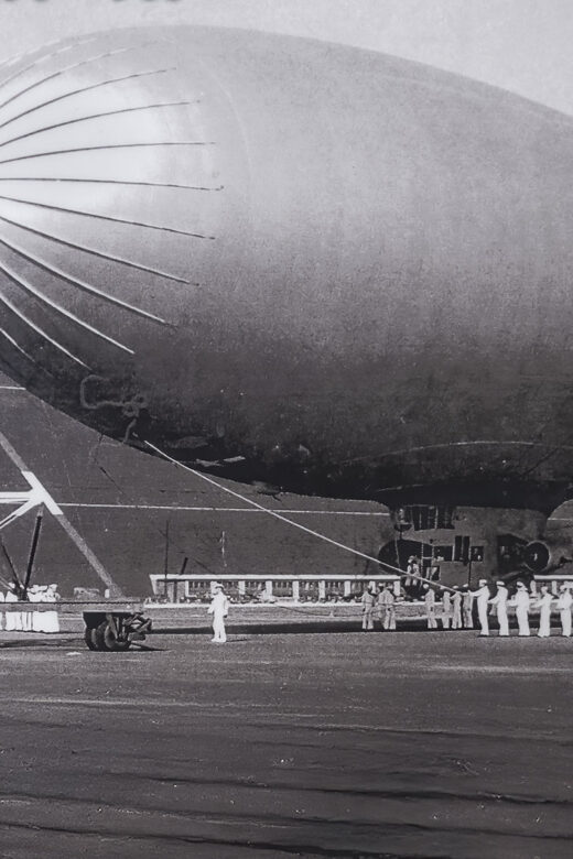 black and white photo of Navy blimp near large hangar