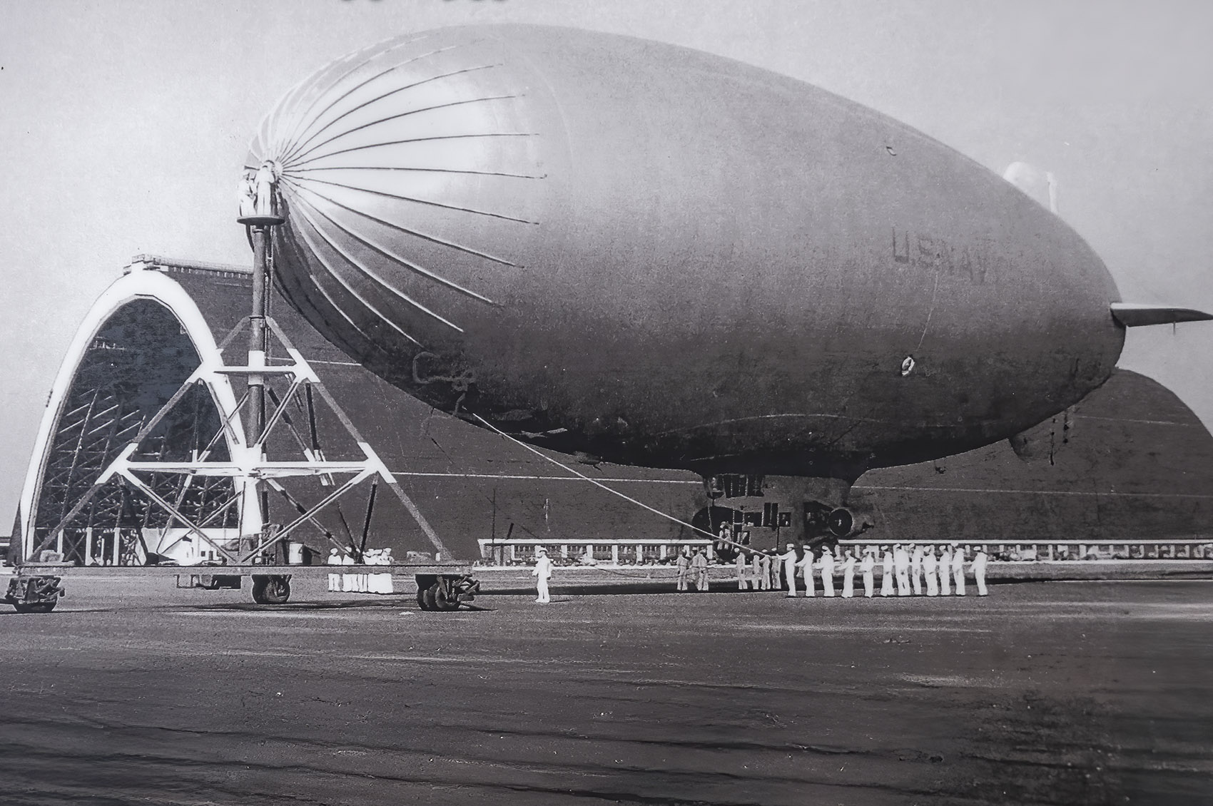 black and white photo of Navy blimp near large hangar