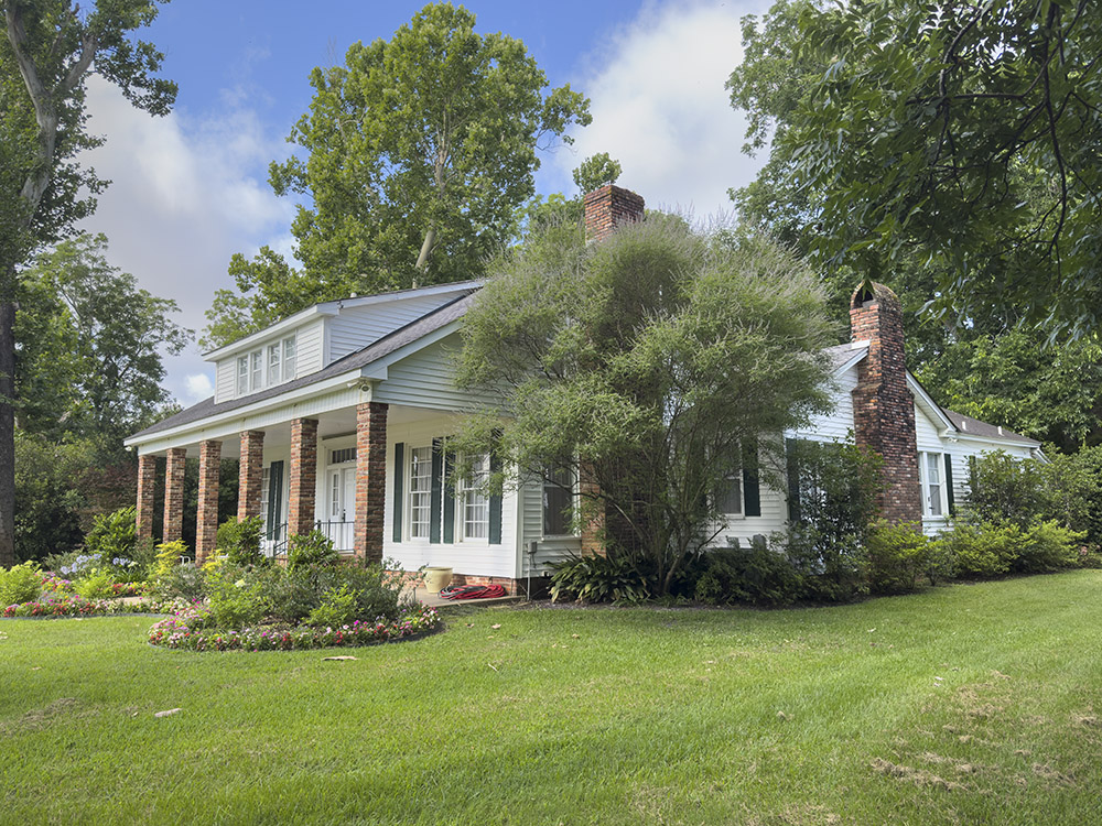 white 1.5 story home with chimney and trees