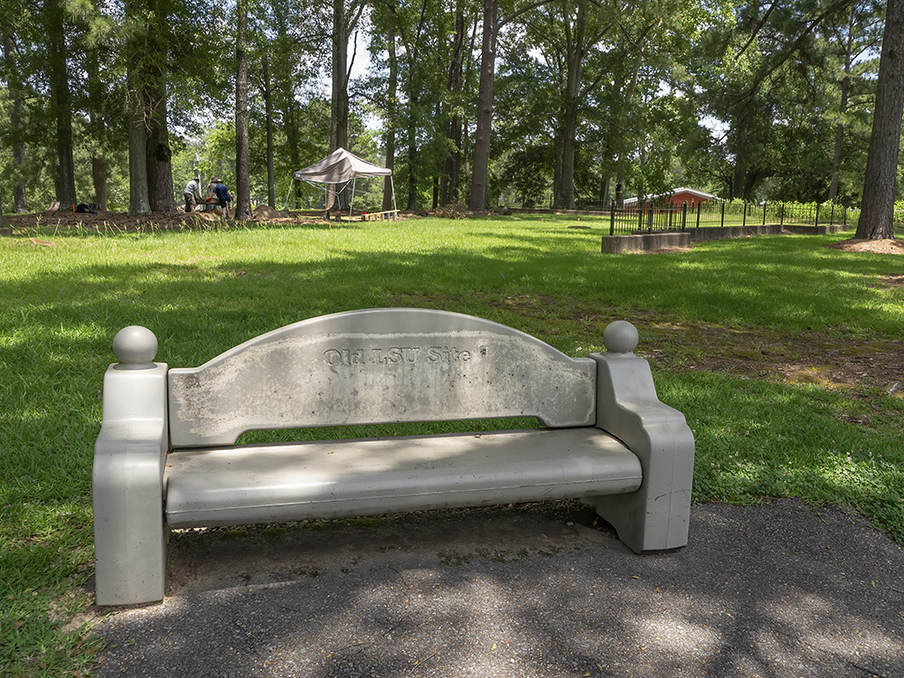 concrete bench near lawn and wooded area marks origin of LSU
