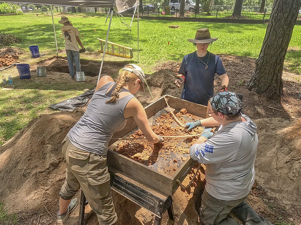 archaeologists sift through dirt at dig site