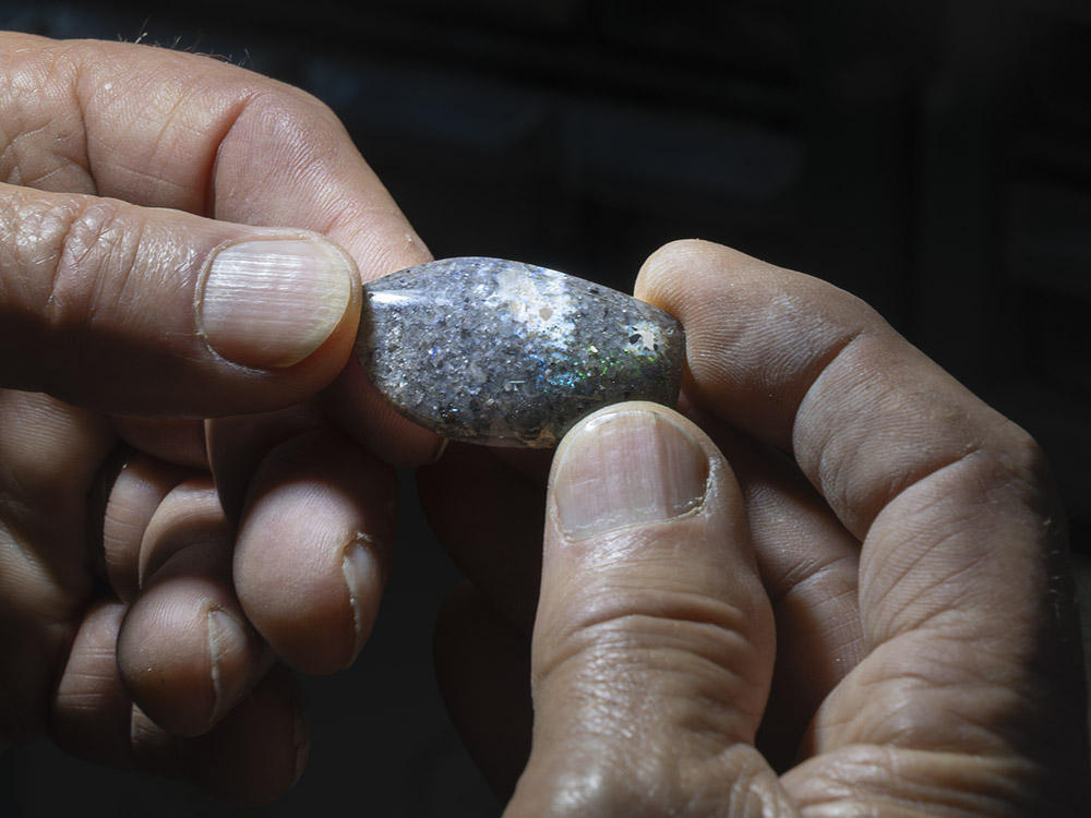 man's hands holding dark Louisiana opal gemstones