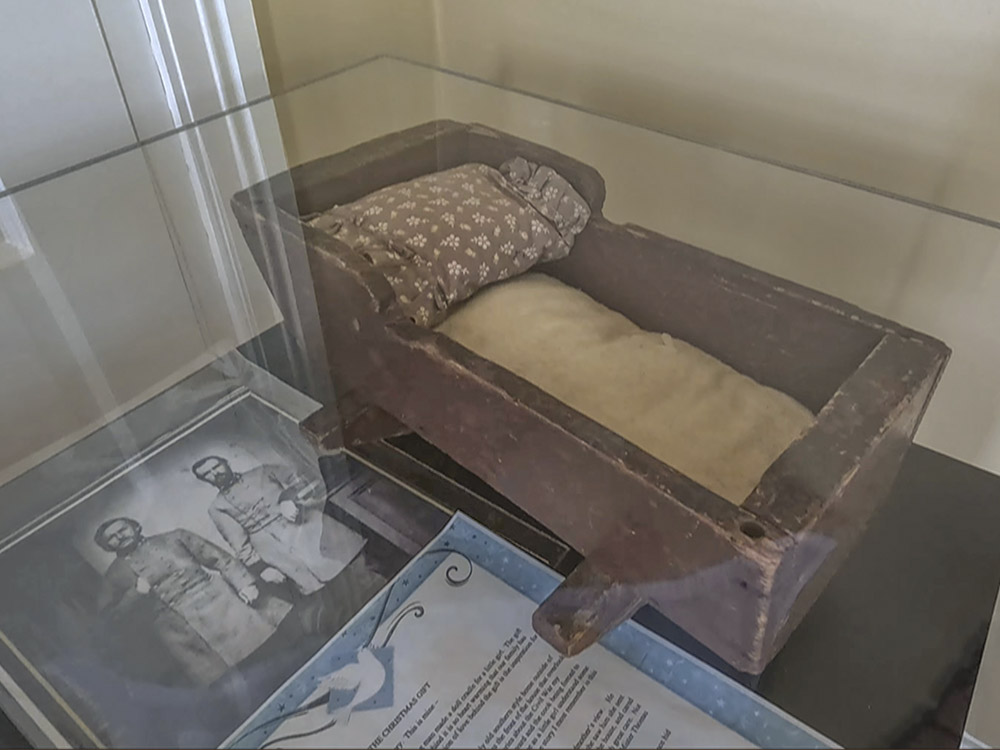 brown wooden doll cradle and picture of civil war soldiers