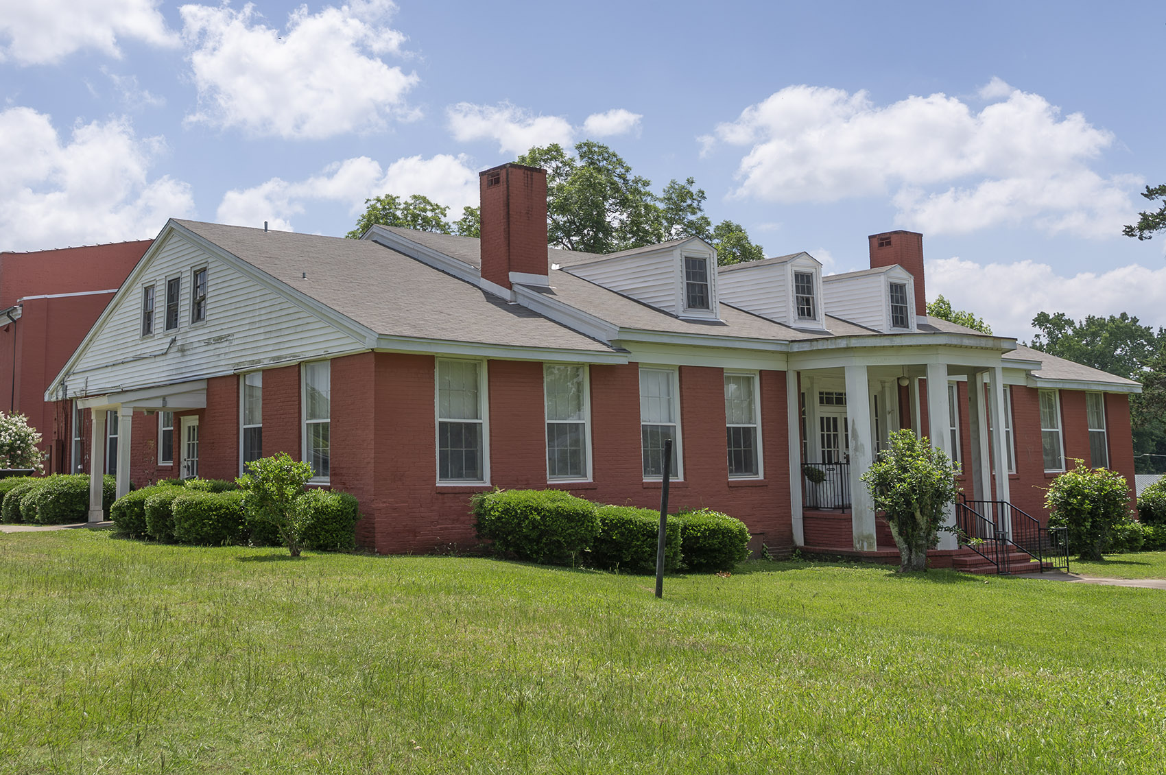 red brick one and a half story house with two chimneys and white columns at entrance