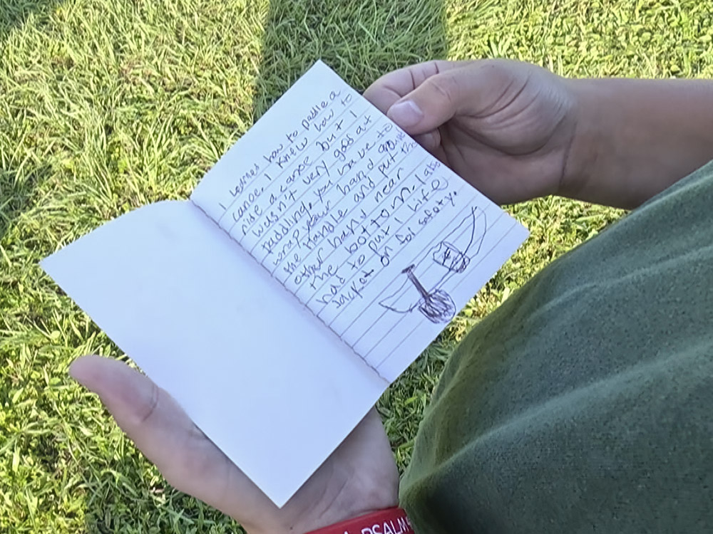 child holding small notebook with handwriting and drawing