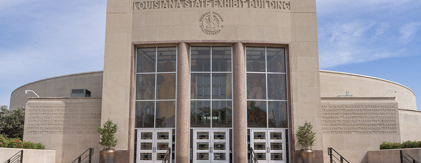 large granite building with large windows and columns and name State Exhibit Museum